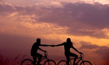 Frau und Mann auf Fahrrädern im Sonnenuntergang